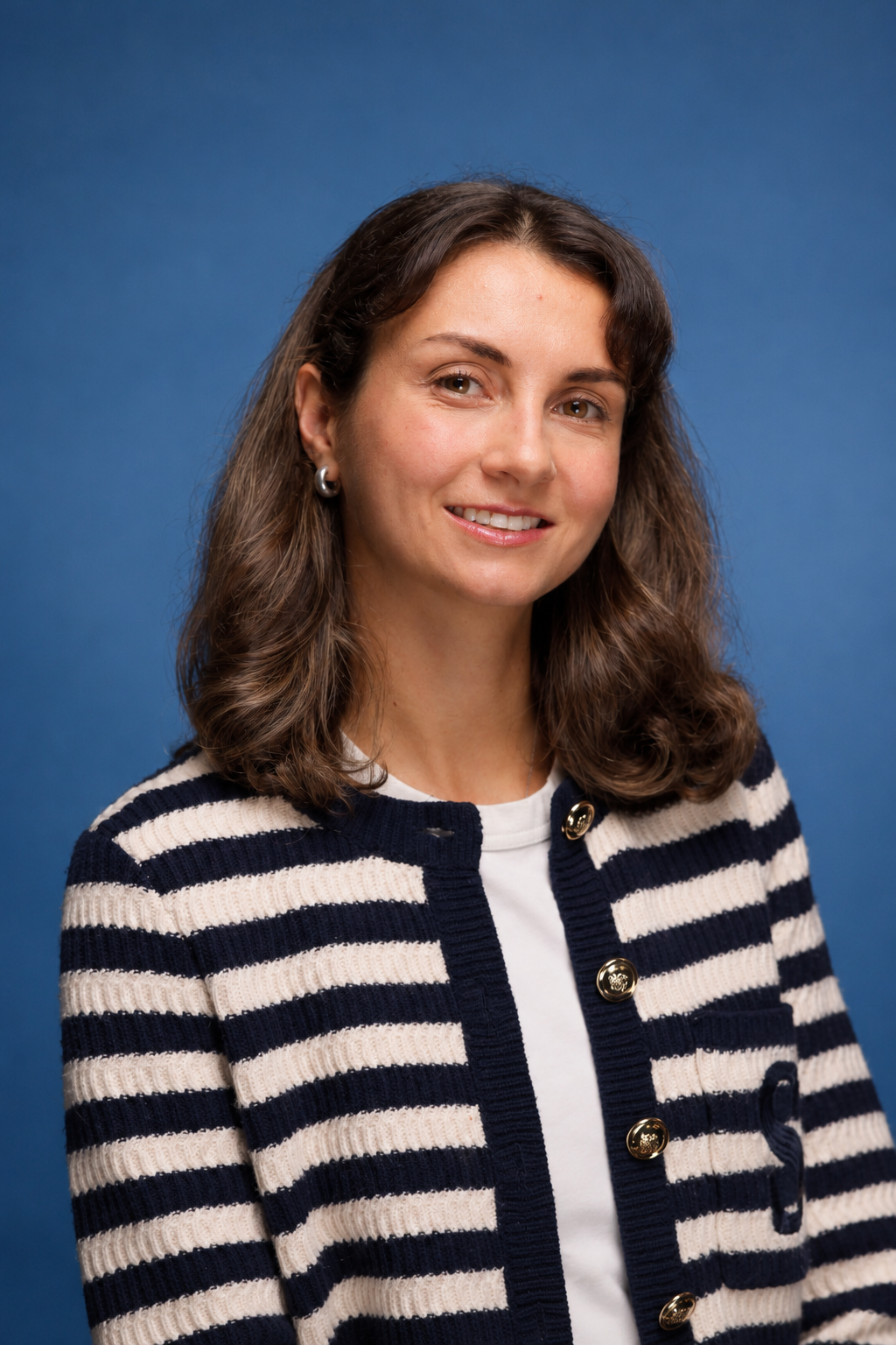 Irinka smiling in a striped cardigan against a blue background